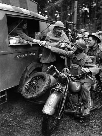 Slide 11 de 100: A motorcyclist of the 1st Canadian Reconnaissance Squadron enjoys a cup of tea during an interlude in the day's work during the Second World War.