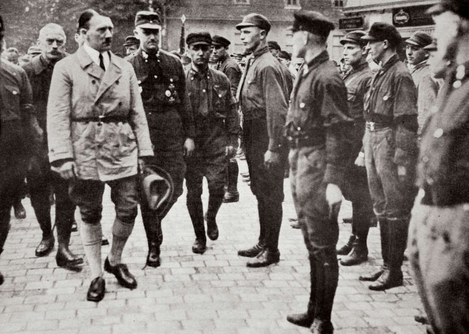 Slide 55 de 100: Hitler inspecting a group of SA Members during World War II, Germany, 1939-1945. Founded in c1919, the Sturmabteilung (SA) was the paramilitary wing of the Nazi party. Its members were known as the 'Brownshirts' because of the colour of their uniforms. The SA played an important part in Hitler's (1889-1945) rise to power in Germany but its significance was effectively ended when its leaders were killed in the 'Night of the Long Knives' in 1934, with the rival Schutzstaffel (SS) taking over its role. Artist Unknown.