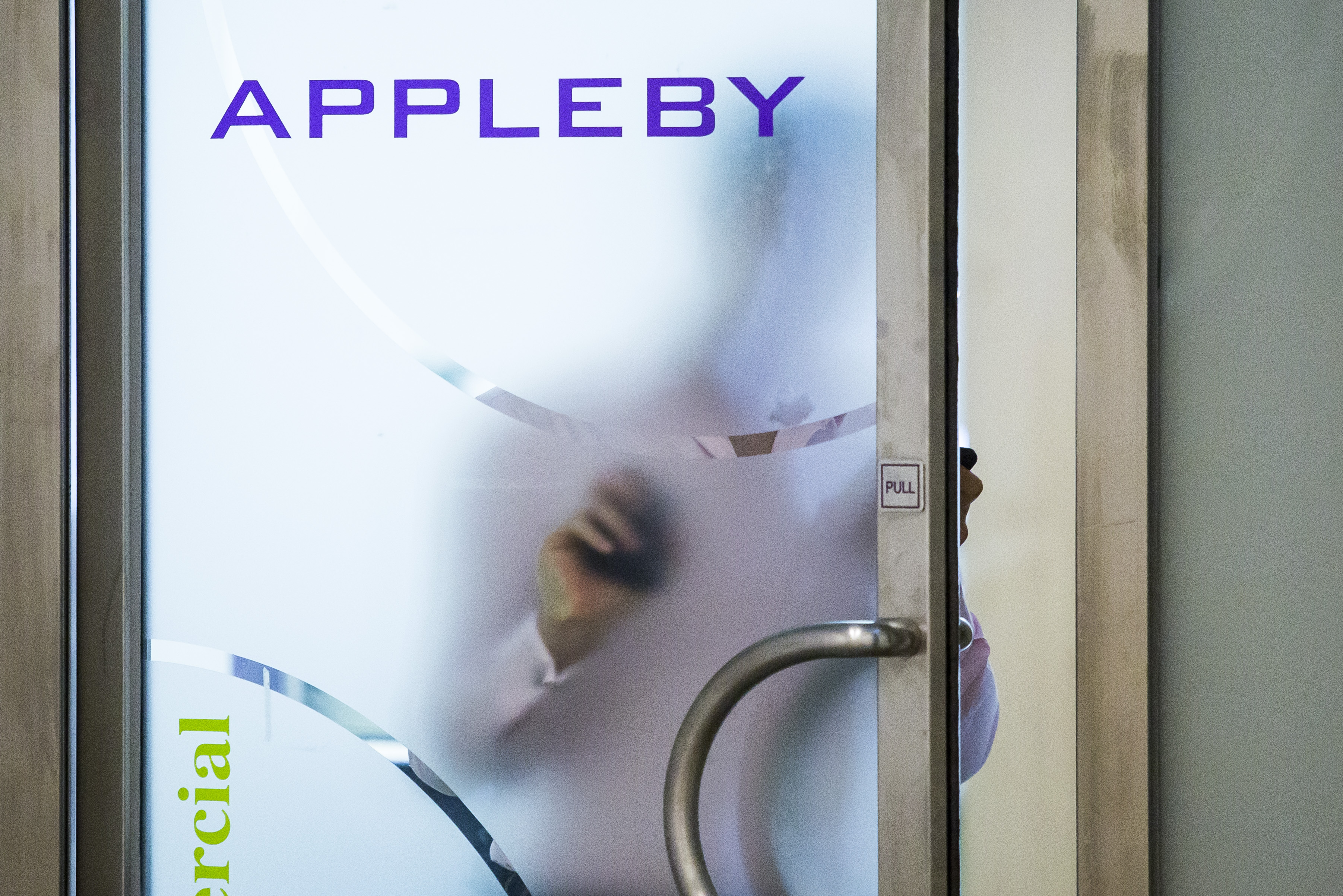 Διαφάνεια 34 από 36: An employee walks through a door at the offices of the law firm Appleby in Hong Kong on November 8, 2017. The Paradise Papers documents, which are mainly from the offshore law firm Appleby, have been shared with international media via the US-based International Consortium of Investigative Journalists.