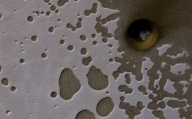 Mars - NASA/JPL-Caltech/University of Arizona/Handout via Reuters Slide 18 of 86: A late summer view of the Southern hemisphere of Mars seen in this image from NASA's Mars Reconnaissance Orbiter released on June 2. Shallow pits are seen in the bright residual cap of carbon dioxide ice. There is also a deeper, circular formation that penetrates through the ice and dust, possibly an impact crater or a collapse pit.
