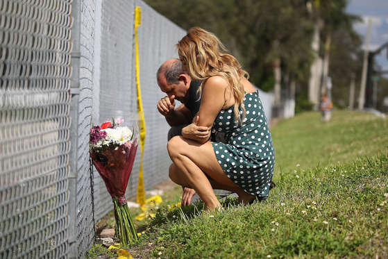 Slide 1 of 68: PARKLAND, FL - FEBRUARY 18:  Maria Cristina and Vincent Collazo pray at the fence that runs around Marjory Stoneman Douglas High School on February 18, 2018 in Parkland, Florida. Police arrested 19 year old former student Nikolas Cruz for the mass shooting that killed 17 people on February 14.
