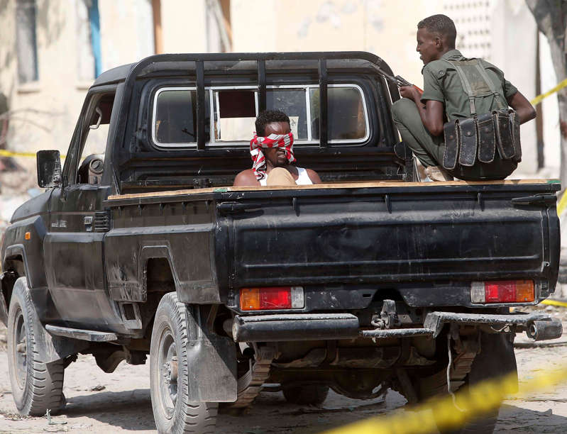 A security officer guards a suspected member of the al Shabaab, who was detained near the Mogadishu port after a suicide car bomb went off at the entrance of the port, in Mogadishu, Somalia