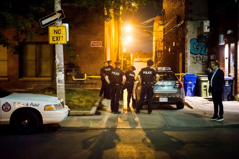 Toronto Mayor John Tory talks on the phone while police look down an alleyway near the site of a shooting in east Toronto, on Sunday, July 22, 2018.
