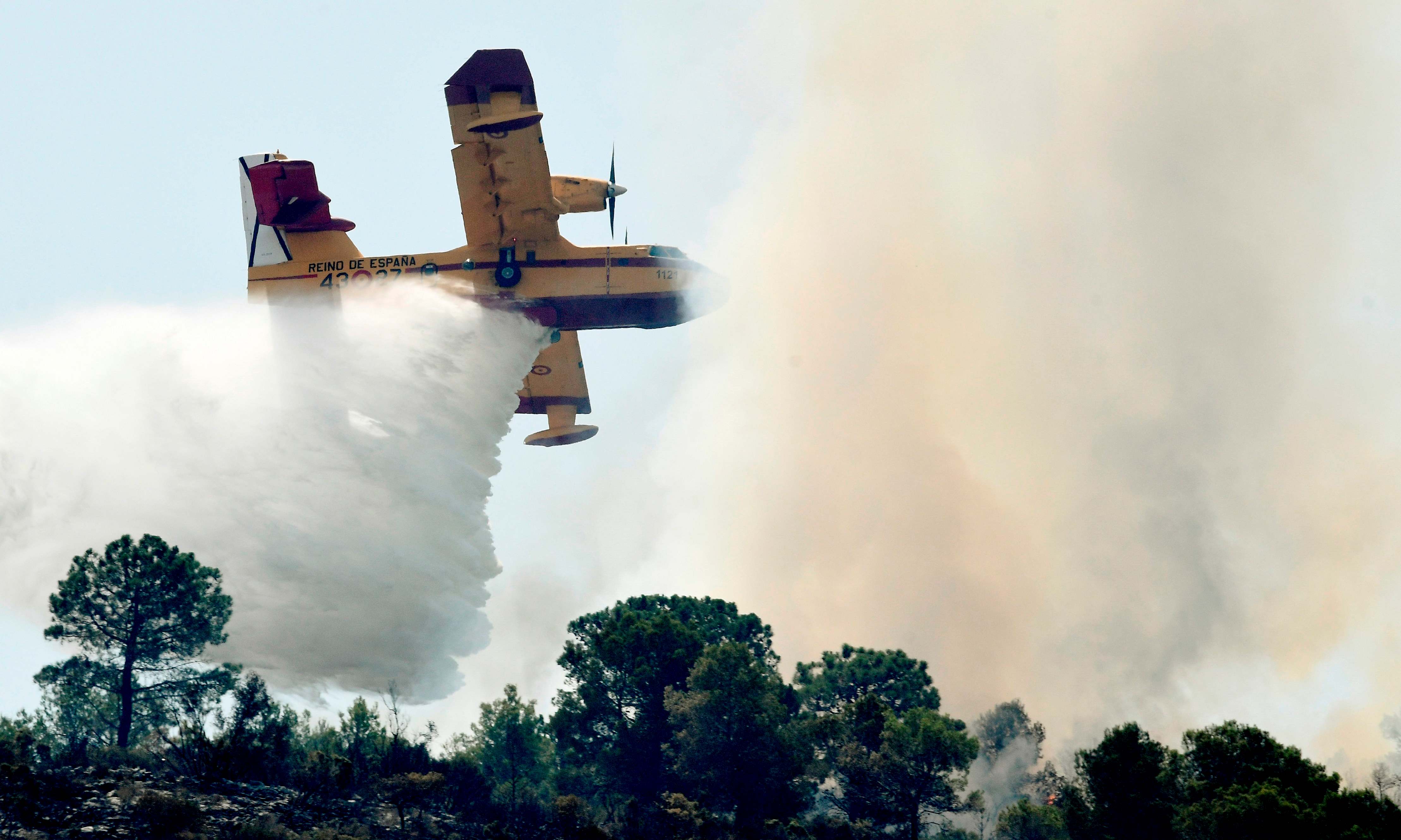 Slide 24 de 33: A seaplane drops water over a wildfire in Pinet, Valencia region, on August 7, 2018. - In the Valencia region, a wildfire that has already devastated a thousand hectares forced to move 2,500 people in the last night.