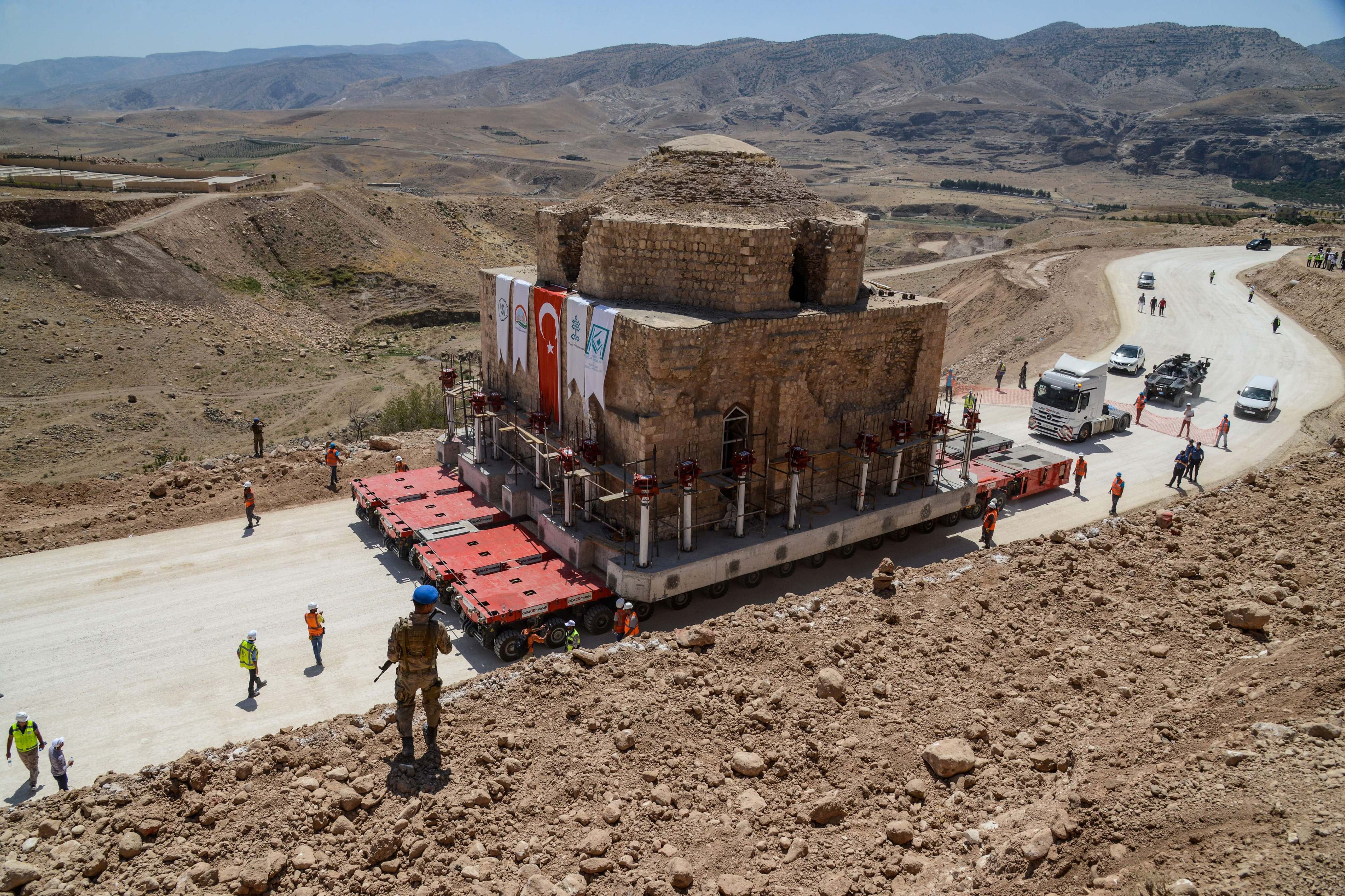 Slide 14 de 33: A Tukish soldier stands guard as the Artuklu Hamam, a centuries-old bath house weighing 1,600 tonnes, is loaded onto a wheeled platform and moved down a specially constructed road, on August 6, 2018, from the southeastern town of Hasankeyf to a new location to avoid being engulfed under floodwaters by a controversial dam project.