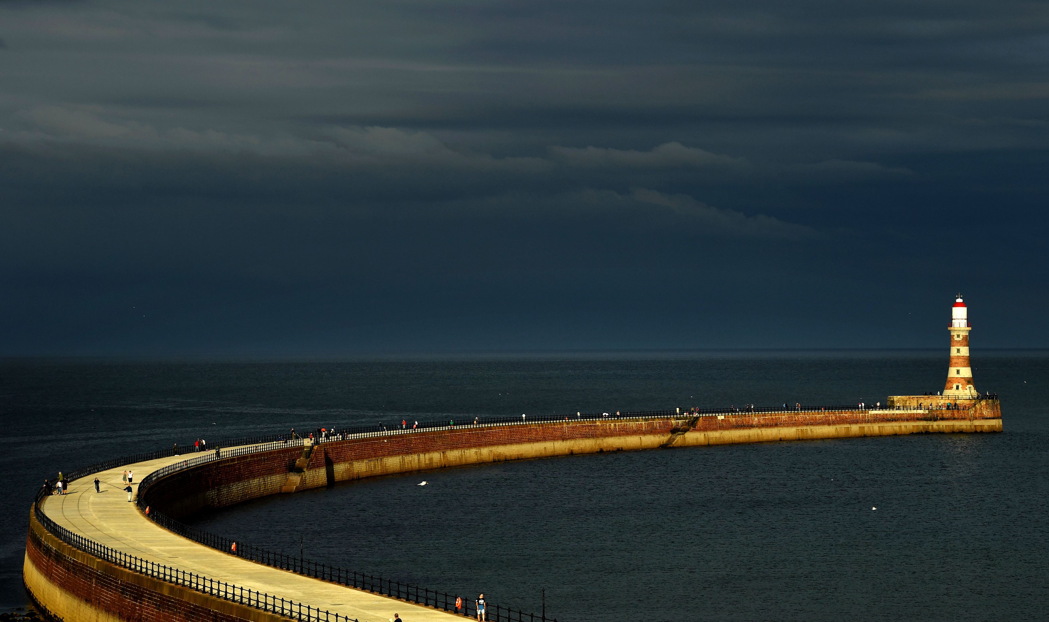 Slide 22 de 33: People walk towards the lighthouse on Roker Pier in Sunderland, north east England, on August 7, 2018. (Photo by PAUL ELLIS / AFP)        (Photo credit should read PAUL ELLIS/AFP/Getty Images)