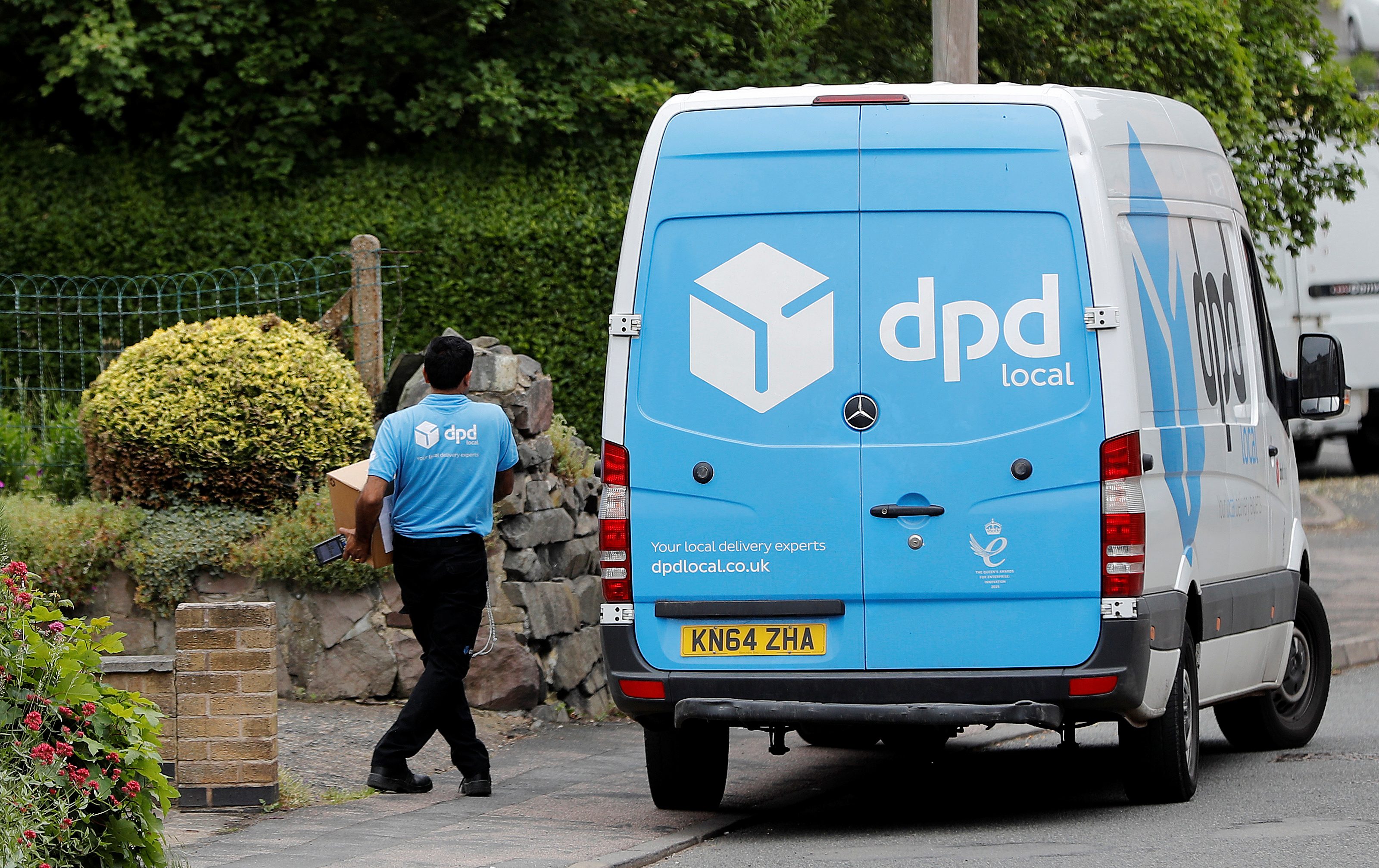 A dpd local delivery driver takes a parcel from his van in Shepshed, Britain June 5, 2018.  REUTERS/Darren Staples