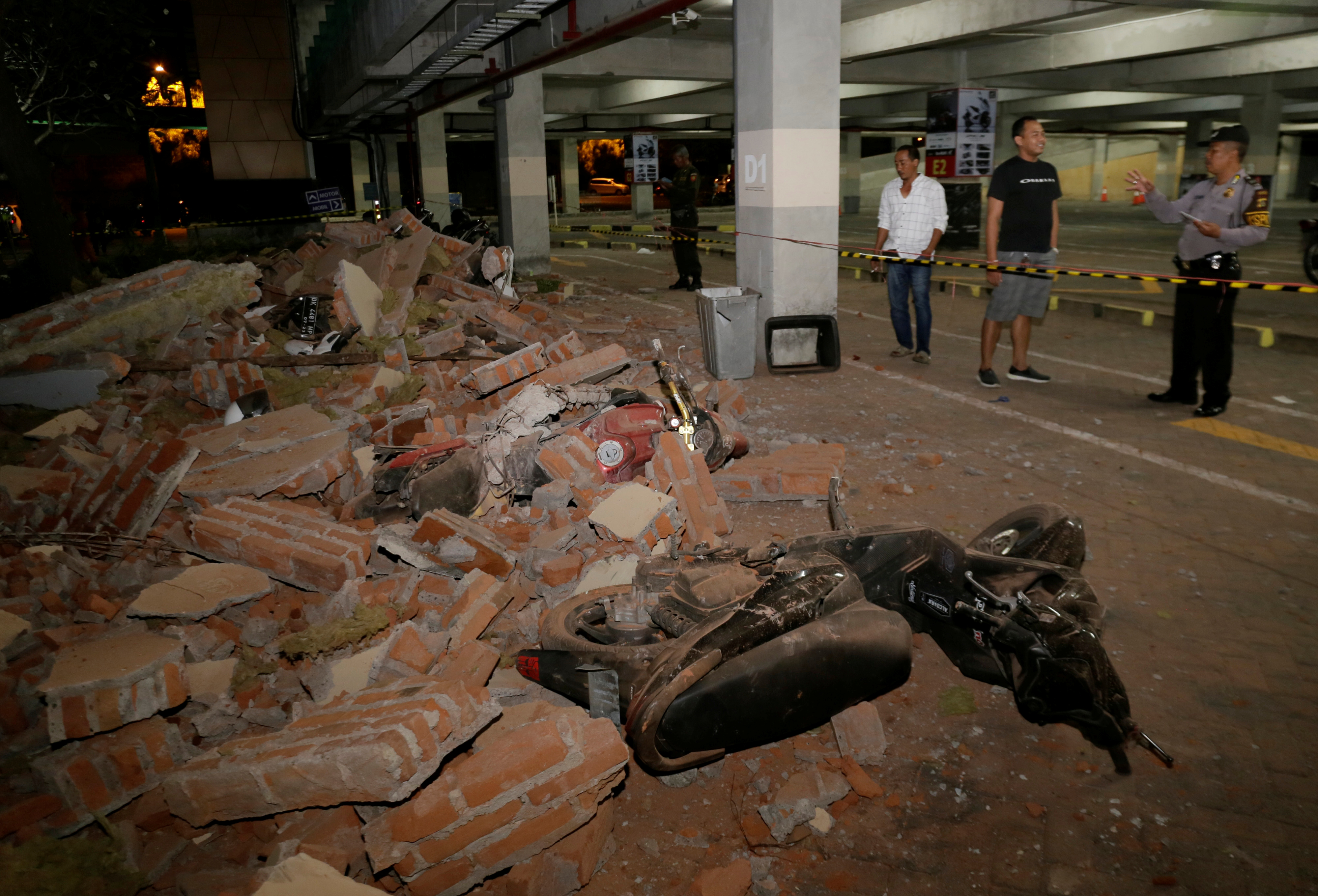 A policeman examines debris that fell and crushed parked motorbikes following a strong earthquake on nearby Lombok island, at a shopping center in Kuta, Bali, Indonesia  August 5, 2018. REUTERS/Johannes P. Christo