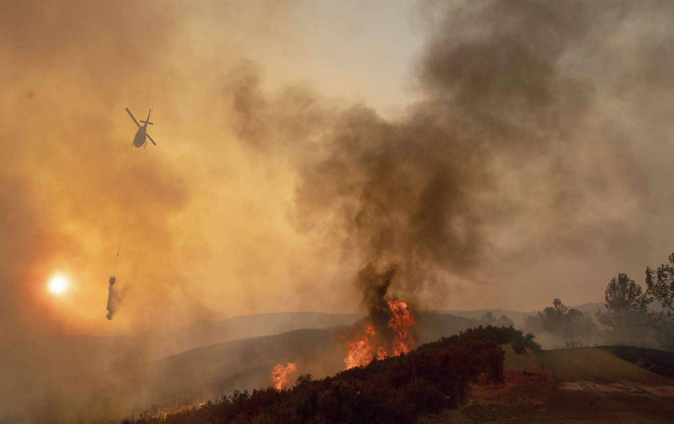 Slide 5 of 95: A helicopter drops water on a burning hillside during the Ranch Fire in Clearlake Oaks, Calif., Sunday, Aug. 5, 2018.