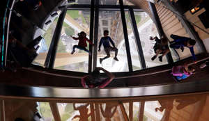 Children lay atop a glass floor, reflected in windows adjacent to it, at the bottom of a new cantilever staircase called the "Oculus Stairs" at the Space Needle Friday, Aug. 3, 2018, in Seattle. The recently completed, $100 million renovation of the 605-foot-tall structure included replacing some floors and walls with structural glass that opened-up views of the three legs below. It also includes "The Loupe," called the world's first and only revolving glass floor. (AP Photo/Elaine Thompson)