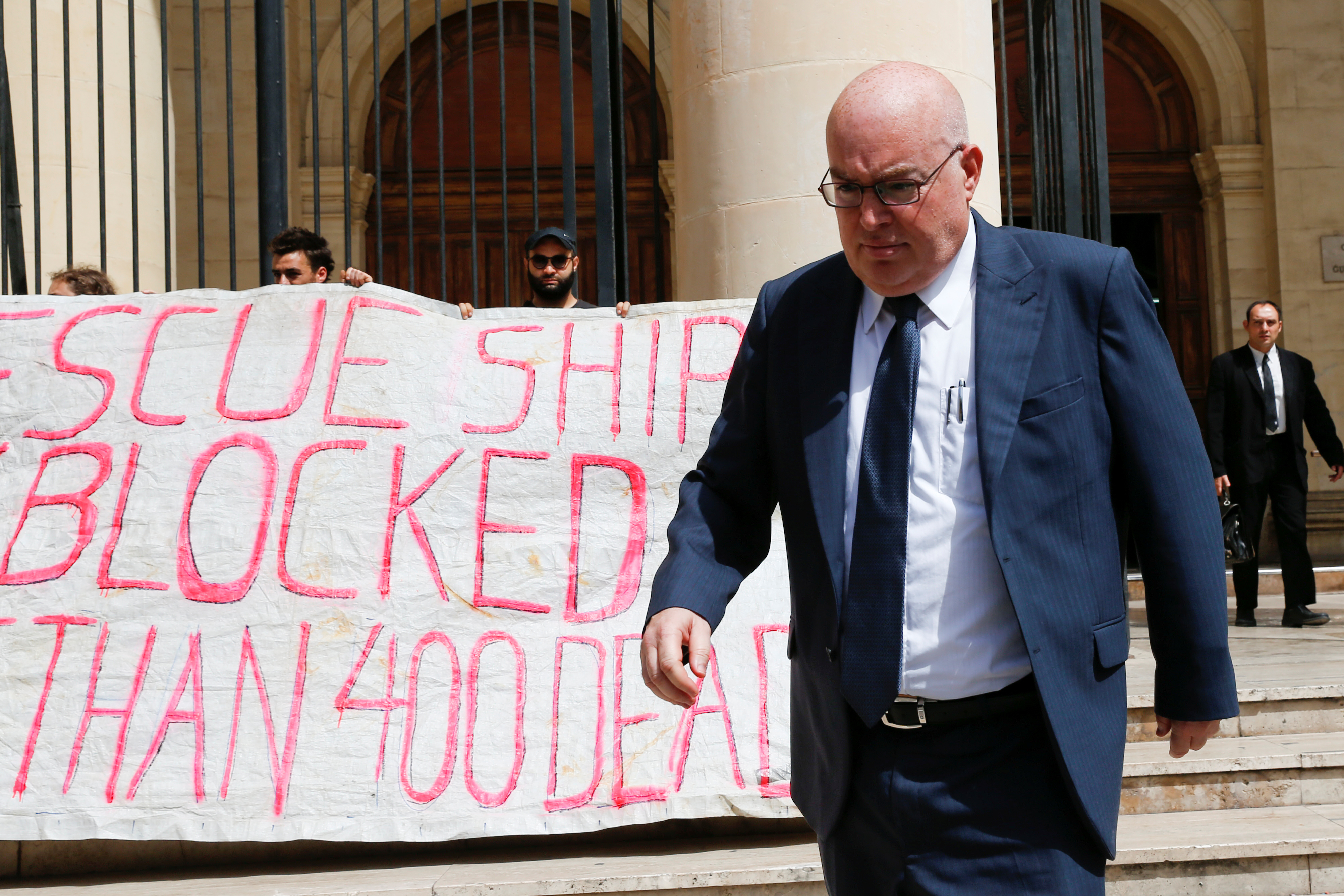Magistrate Joseph Mifsud walks past crew members of NGO Sea-Watch protesting outside the Courts of Justice during the arraignment of Claus-Peter Reisch, the captain of the charity ship MV Lifeline in Valletta, Malta July 2, 2018. REUTERS/Darrin Zammit Lupi