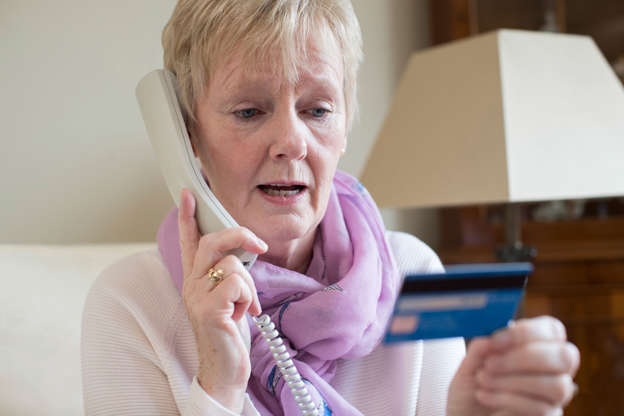 Lady on the phone to the bank while holding a credit card