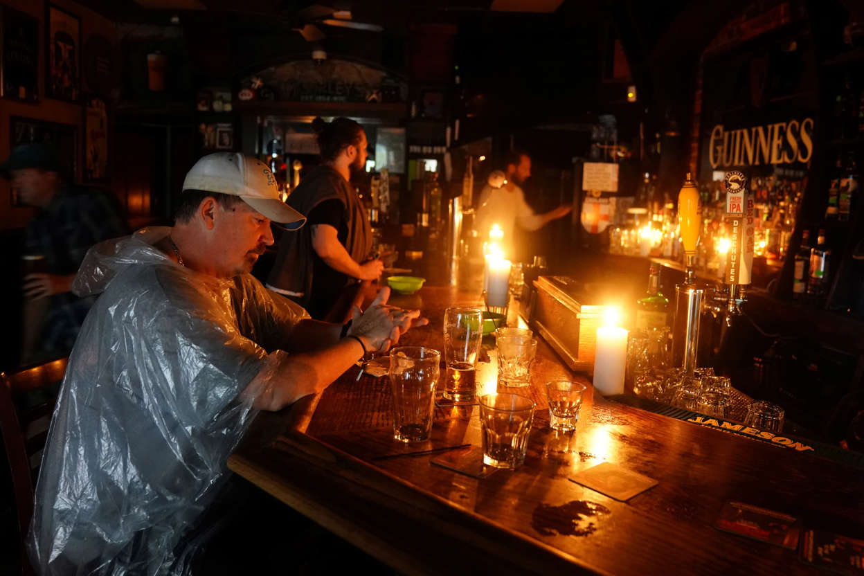 Slide 4 of 69: People sit at a bar that has no power and drink during a "Hurricane Party" as Hurricane Florence comes ashore on Wilmington, North Carolina, U.S., September 14, 2018. REUTERS/Carlo Allegri - RC153D8D9800
