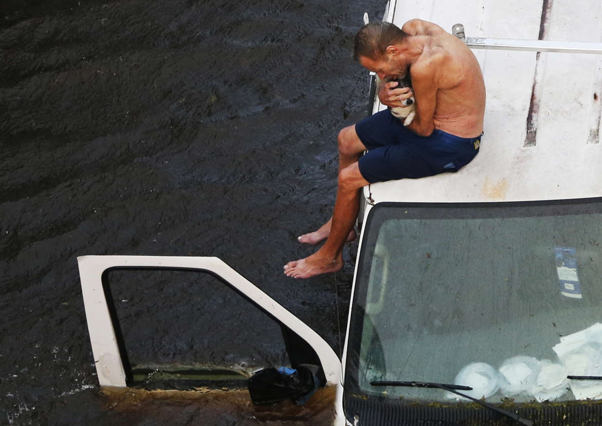 Slide 4 of 86: Willie Schubert of Pollocksville, N.C., cradle his dog Lucky as he waits to be rescued by a U.S. Coast Guard helicopter crew off a stranded van in Pollocksville, Monday, Sept. 17, 2018, in the aftermath of Hurricane Florence.