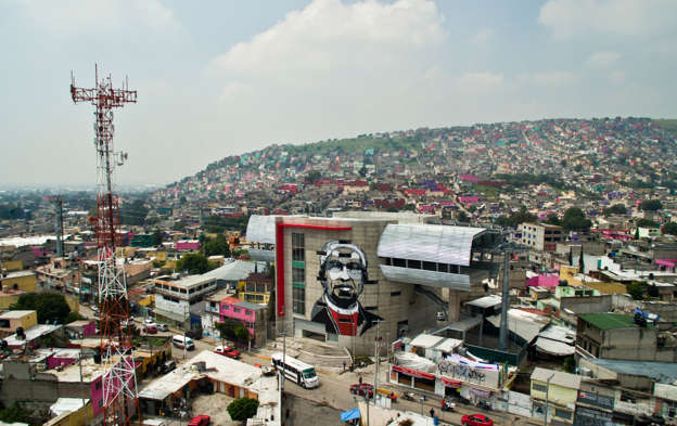 View of a cable car station decorated with a mural of Icelandic artist Guido Van Helten  at a poor neighborhood in Ecatepec, Mexico on August 25, 2016. Dozens of murals were painted on buildings in a poor neighborhood in Ecatepec, on the route of a new cable car that will run this year.