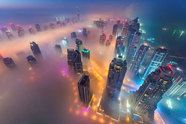 Aerial view of cityscape with illuminated skyscrapers above the clouds in Dubai, United Arab Emirate... - Mint Images/Getty Images Slide 3 de 24: Aerial view of cityscape with illuminated skyscrapers above the clouds in Dubai, United Arab Emirates at dusk.