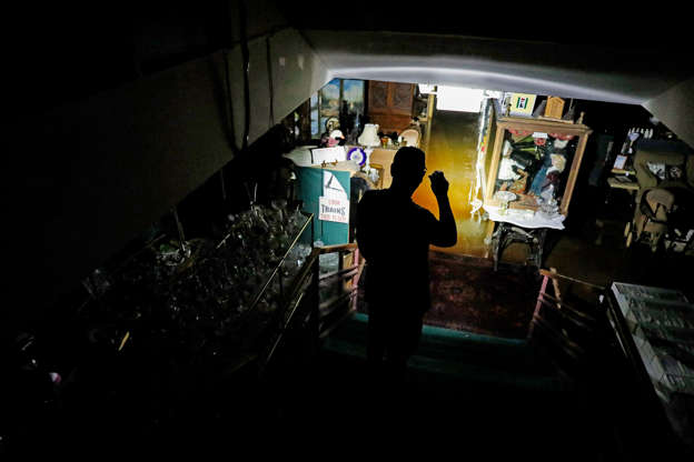 Slide 3 of 77: Chris Allen looks into the flooded lower level of an antique shop during a power outage in the aftermath of hurricane Michael in Panama City, Fla., Thursday, Oct. 11, 2018. (AP Photo/David Goldman)