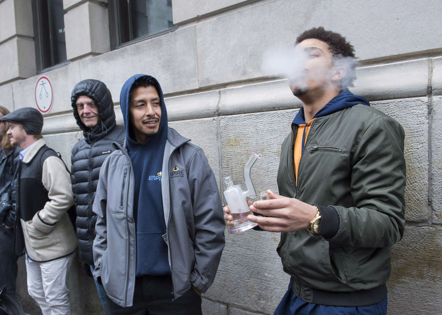 A man smokes from a bong as he waits in line to purchase legal cannabis outside a government cannabi... - THE CANADIAN PRESS/Graham Hughes Slide 18 of 31: A man smokes from a bong as he waits in line to purchase legal cannabis outside a government cannabis store in Montreal, Wednesday, October 17, 2018.