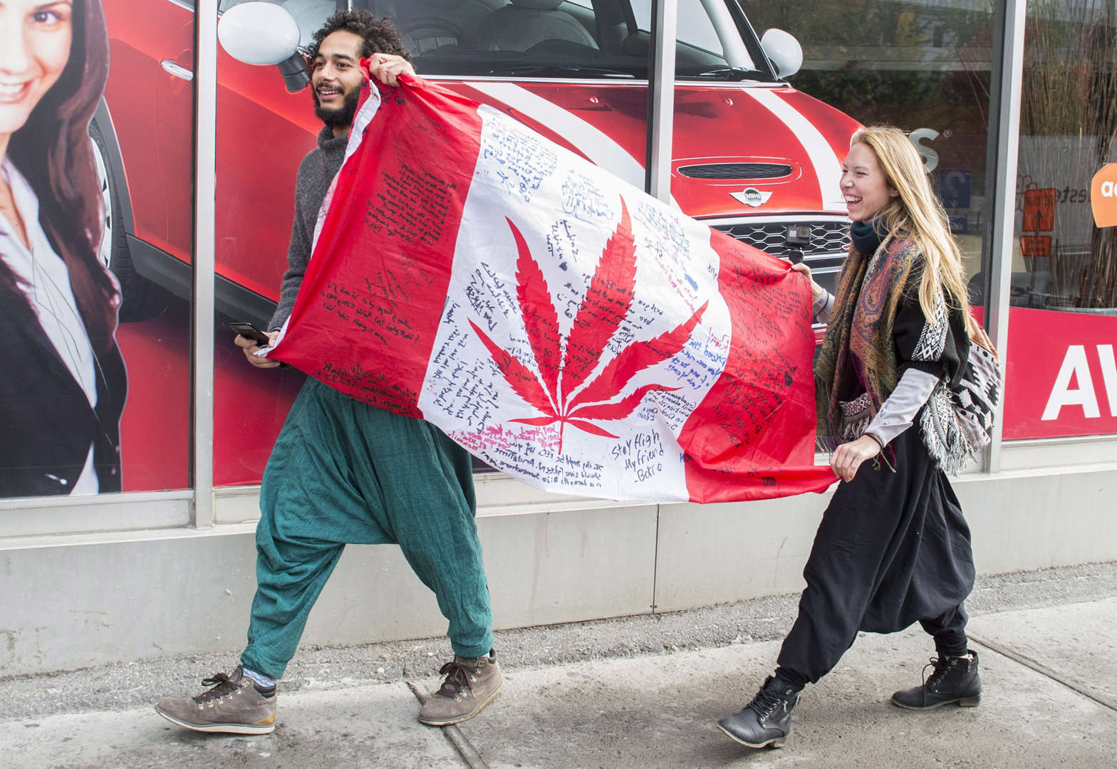 People hold up a Canadian flag with a marijuana logo on it outside a government cannabis store in Mo... - THE CANADIAN PRESS/Graham Hughes Slide 10 of 31: People hold up a Canadian flag with a marijuana logo on it outside a government cannabis store in Montreal, Wednesday, October 17, 2018.