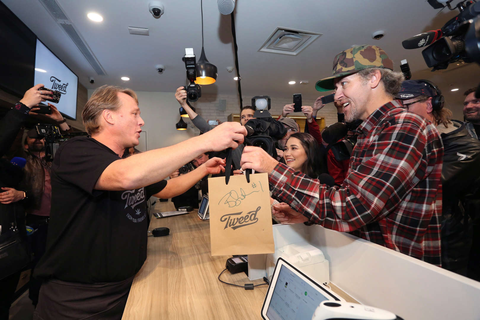 Canopy Growth CEO Bruce Linton, left to right, passes a bag with the first legal cannabis for recrea... - THE CANADIAN PRESS/Paul Daly Slide 8 of 31: Canopy Growth CEO Bruce Linton, left to right, passes a bag with the first legal cannabis for recreation use sold in Canada to Nikki Rose and Ian Power at the Tweed shop on Water Street in St. John's N.L. at 12:01 am NDT on Wednesday October 17, 2018.