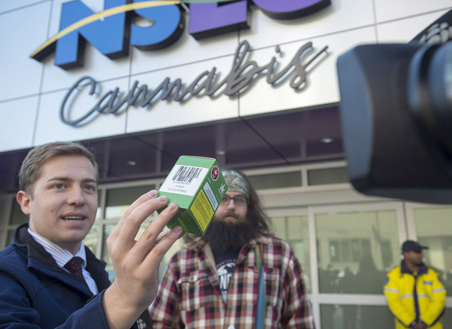 A customer waits as a journalist displays his purchase outside the Nova Scotia Liquor Corporation ca... - THE CANADIAN PRESS/Andrew Vaughan Slide 3 of 31: A customer waits as a journalist displays his purchase outside the Nova Scotia Liquor Corporation cannabis story in Halifax on Oct. 17, 2018.