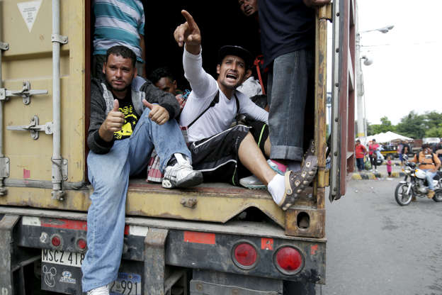 Slide 4 of 12: Honduran migrants making their way to the U.S. as a group, get a free ride in the back of a driver