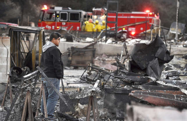 Slide 4 of 50: Ricky Alvarado looks over the charred remains of his home at the Seminole Springs Mobile Home Park, Sunday, Nov. 11, 2018, after the neighborhood was devastated by wildfires in Agoura Hills, Calif.