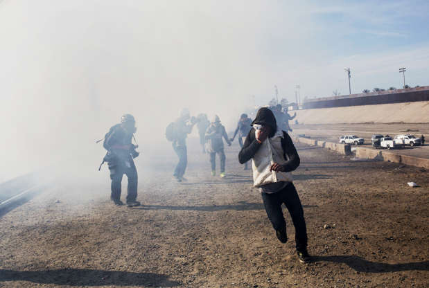 Slide 4 of 50: Migrants run from tear gas launched by U.S. agents, amid photojournalists covering the Mexico-U.S. border, after a group of migrants got past Mexican police at the Chaparral crossing in Tijuana, Mexico, Sunday, Nov. 25, 2018.