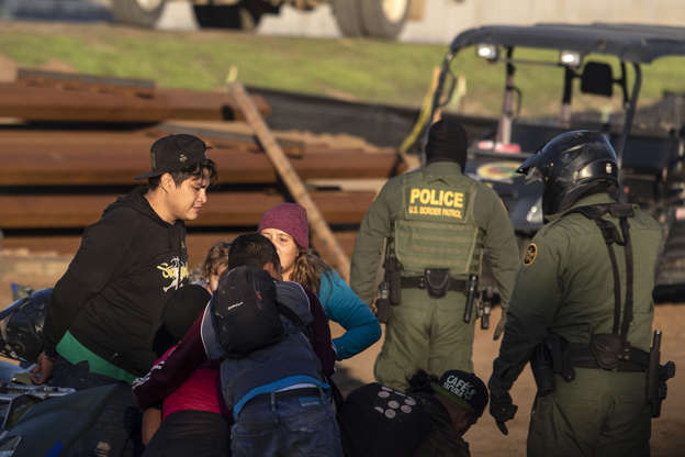 Slide 3 of 50: Central American migrants, travelling in a caravan, are taken in custody by US border patrol officers after crossing the Mexico-US border fence to San Diego County, as seen from Playas de Tijuana, Baja California state, Mexico on December 13, 2018. (Photo by Guillermo Arias / AFP)        (Photo credit should read GUILLERMO ARIAS/AFP/Getty Images)