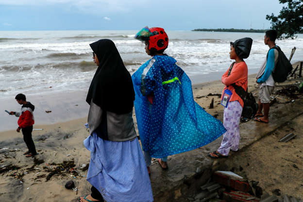 Slide 4 of 33: Local residents affected by the tsunami stand at Carita beach in Pandeglang, Banten province, Indonesia, December 24, 2018. REUTERS/Jorge Silva - RC1ABD411D20