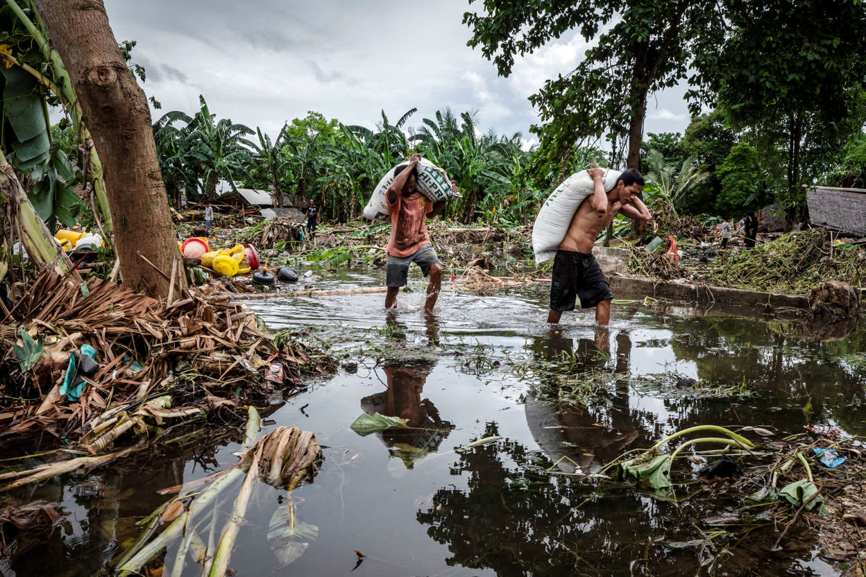 Slide 3 of 43: Villagers walks through debris after hit by tsunami as they carry their belonging on December 24, 2018 in Carita, Banten province,  Indonesia. Over 280 people have reportedly been killed after a volcano-triggered tsunami hit the coast around Indonesia's Sunda Strait on Saturday night, injuring at least 1,016 people.