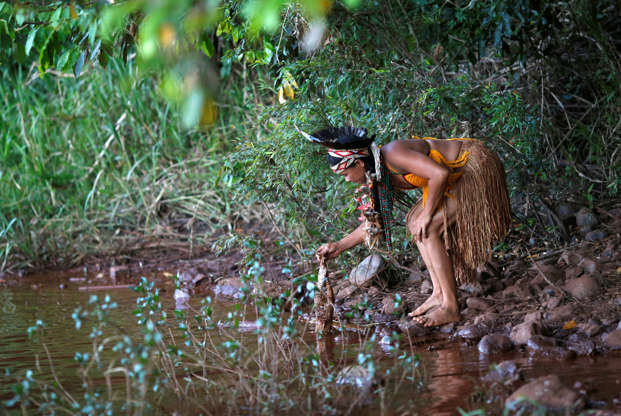 Slide 4 de 75: Índia da tribo Pataxo Ha-ha-hae segura peixe morto próximo ao rio Paraopeba