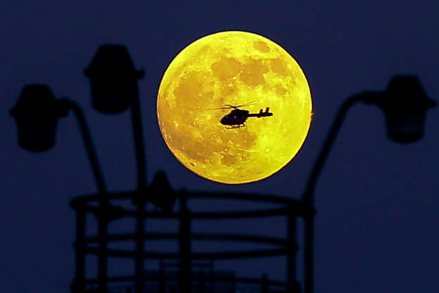 Slide 3 of 29: A helicopter flies in front of the Wolf Moon as it rises over the capital. The Wolf Moon, the Full Moon on January 20-21, 2019, is a Supermoon, making it look bigger and brighter than usual during the total lunar eclipse.