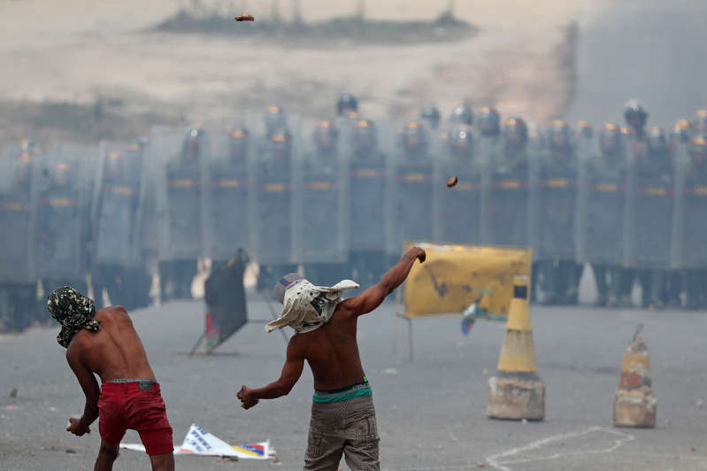 Manifestantes atiram pedras contra militares venezuelanos na fronteira com o Brasil