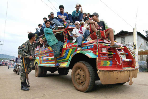Slide 28 de 45: LAMITAN, PHILIPPINES:  A Philippine soldier (L) stops an overloaded 'jeepney' for inspection in the mixed Muslim-Christian town of Lamitan in the southern Philippine island of Basilan, 09 May 2004. Fears of attacks from Muslim Abu Sayyaf rebels and feuding warlords are threatening the conduct of polls here a day before the presidential elections.   AFP PHOTO/JAY DIRECTO  (Photo credit should read JAY DIRECTO/AFP/Getty Images)