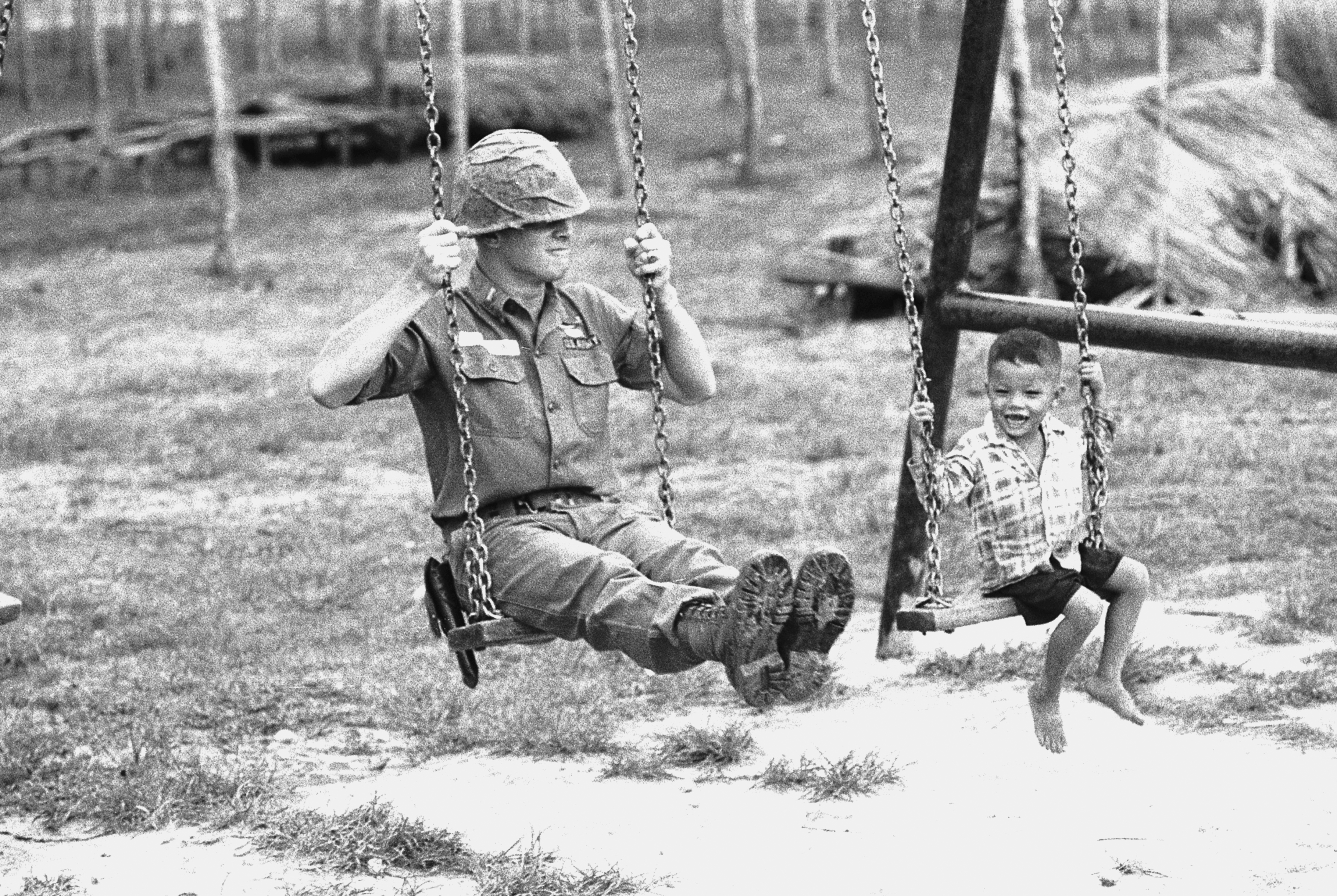Slide 6 of 50: A young Vietnamese child and a U.S. soldier of the 25th infantry division test a swingset in a new playground at the American base in Cu Chi, Vietnam. The playground, part of an improvement project, was built by members of the 25th.
