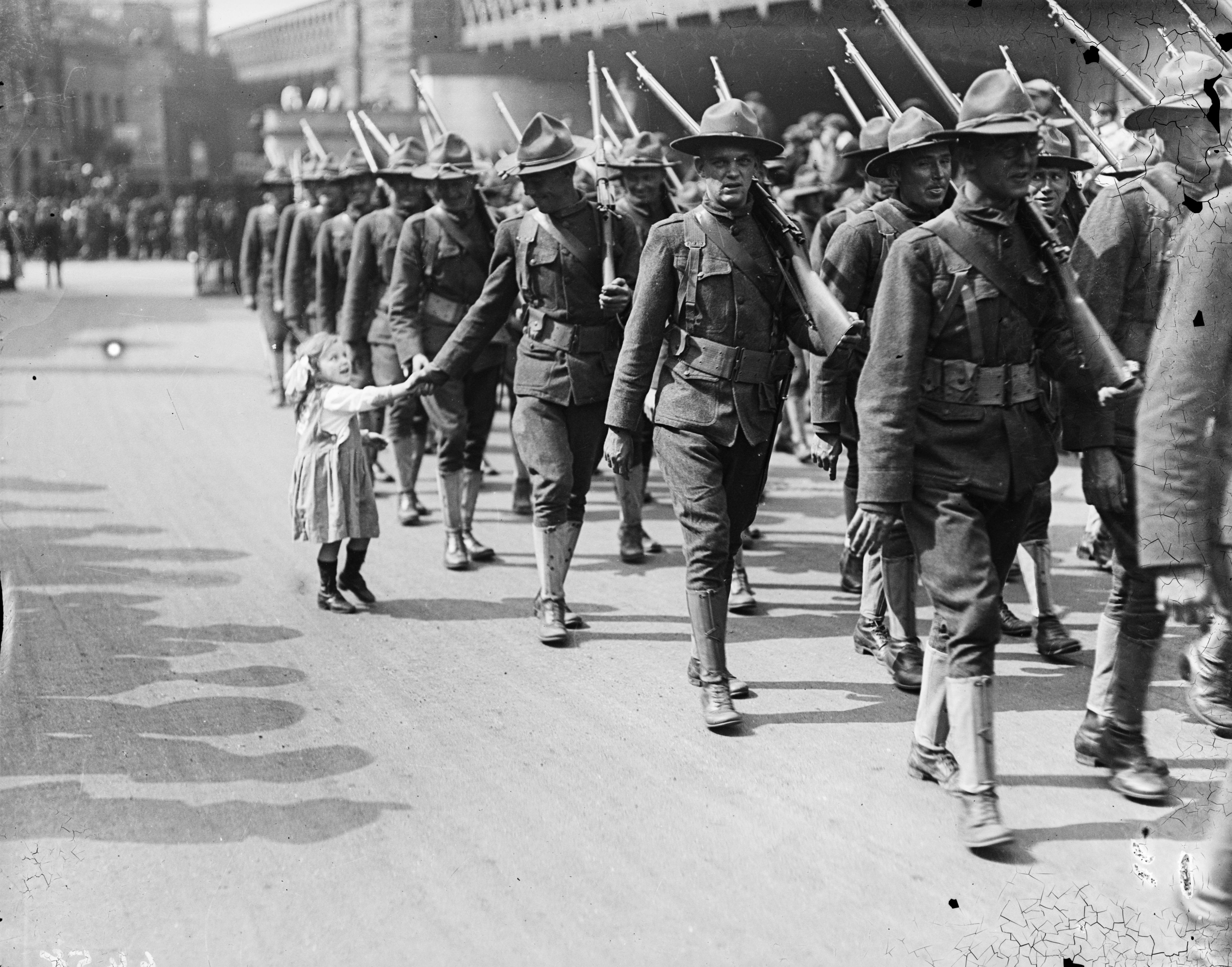 Slide 3 of 50: 15th August 1917: A little girl has her hand shaken by an American soldier as his troop parade through the streets of London. (Photo by A. R. Coster/Topical Press Agency/Getty Images)