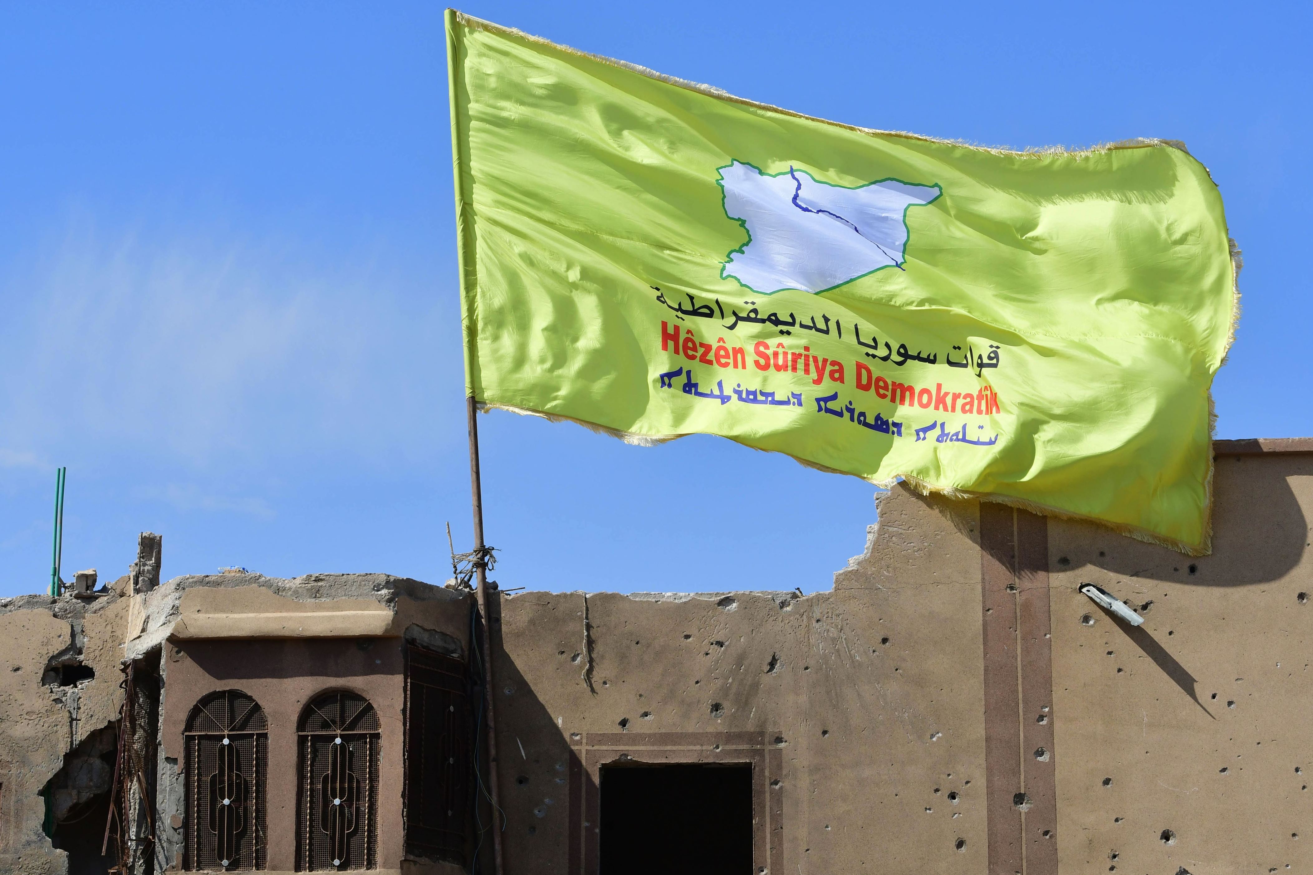 A picture taken on March 23, 2019 shows the US-backed Syrian Democratic Forces' (SDF) flag atop a building in the Islamic State group's last bastion in the eastern Syrian village of Baghuz after defeating the jihadist group. - The Kurdish-led forces pronounced the death of the Islamic State group's nearly five-year-old 'caliphate' on March 23, 2019 after flushing out diehard jihadists from their very last bastion in eastern Syria. (Photo by GIUSEPPE CACACE / AFP)        (Photo credit should read GIUSEPPE CACACE/AFP/Getty Images)