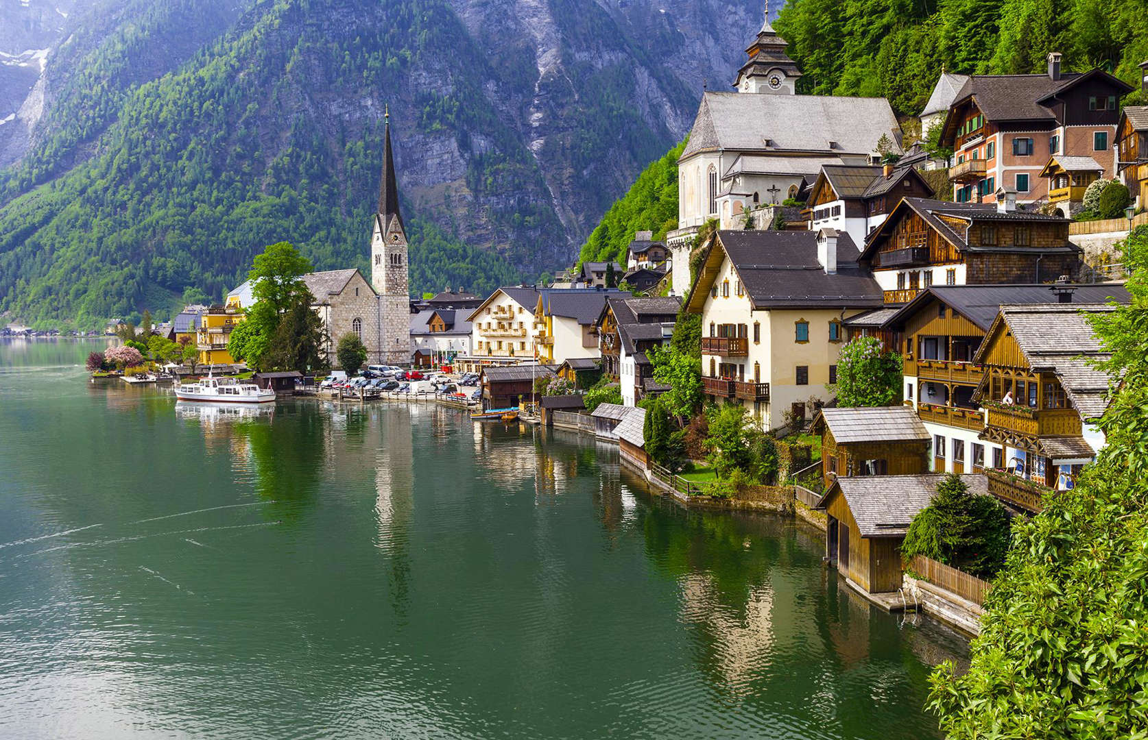 Slide 3 of 51: Driving to Hallstatt, located in Austria's mountainous Salzkammergut region, isn't easy, however, upon arrival you'll be rewarded with the most incredible storybook town you could've ever wished for. The 16th-century traditional Alpine houses are perched on a narrow cliffside, facing the Lake Hallstatt, with dramatic mountain views in the background, making it impossibly beautiful.