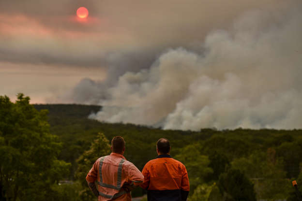 Slide 1 of 49: TOPSHOT - Residents watch a large bushfire as seen from Bargo, 150km southwest of Sydney, on December 19, 2019. - A state of emergency was declared in Australia's most populated region on December 19 as an unprecedented heatwave fanned out-of-control bushfires, destroying homes and smothering huge areas with a toxic smoke.