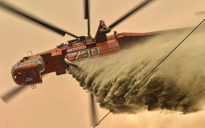 Slide 2 of 49: A helicopter drops fire retardent to protect a property in Balmoral, 150 kilometres southwest of Sydney on December 19, 2019. - A state of emergency was declared in Australia's most populated region on December 19, as a record heat wave fanned unprecedented bushfires.
