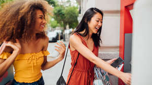 a young girl standing next to a woman: When you use an ATM that is outside of your network, your bank and the ATM might both charge you fees. Find a bank with plenty of ATMs in the places you frequent or with a wide network of partners to save.