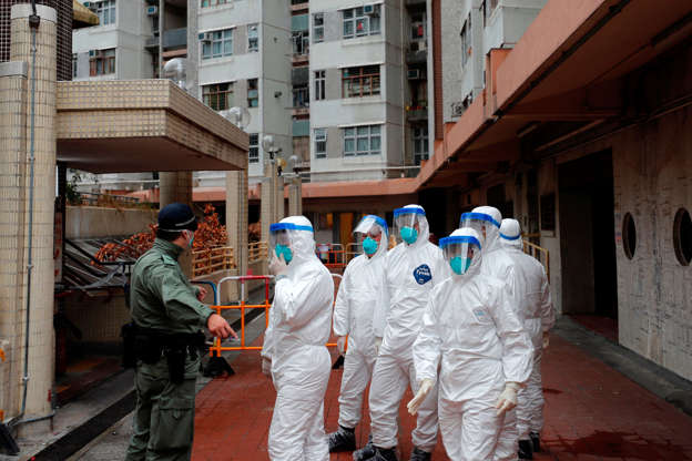 الشريحة 2 من 26: Police in protective gear wait to evacuate residents from a public housing building, following the outbreak of the novel coronavirus, in Hong Kong, China February 11, 2020. REUTERS/Tyrone Siu