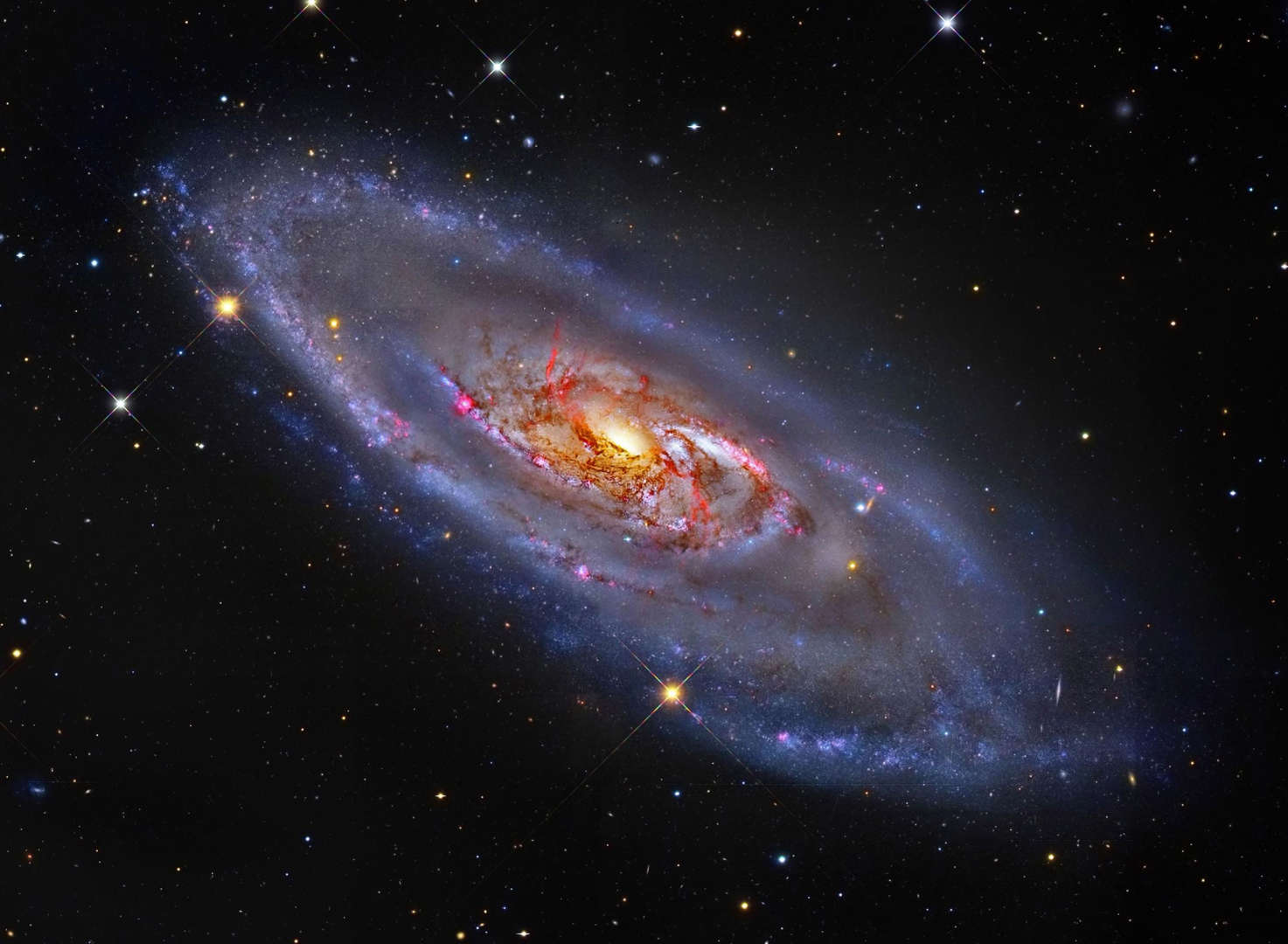 What's happening at the center of spiral galaxy M106? A swirling disk of stars and gas, M106's appearance is dominated by blue spiral arms and red dust lanes near the nucleus, as shown in the featured image. The core of M106 glows brightly in radio waves and X-rays where twin jets have been found running the length of the galaxy. An unusual central glow makes M106 one of the closest examples of the Seyfert class of galaxies, where vast amounts of glowing gas are thought to be falling into a central massive black hole.