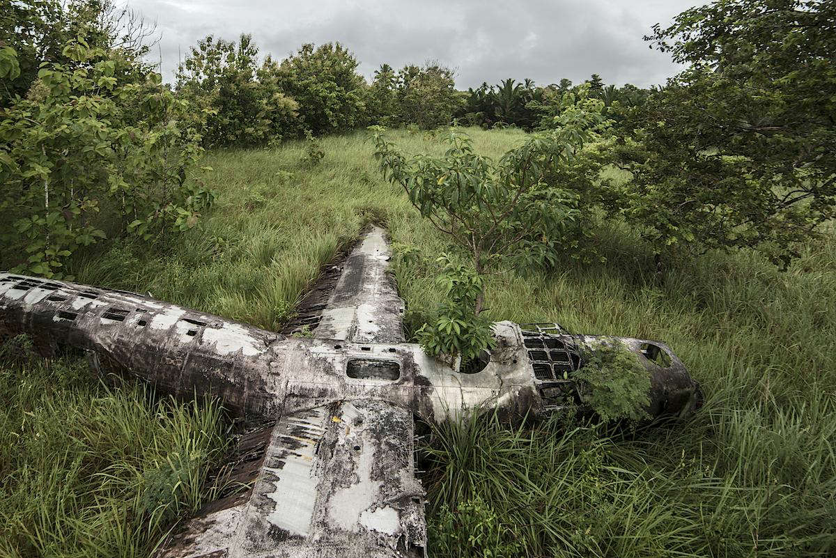 Slide 26 of 28: Another World War II workhorse, the massive B-24 bomber crash-landed in swamp of Papua New Guinea forest. All nine airmen flying on the plane miraculously survived. The locals call the wreck ‘Swamp Ghost.’ After a dull, rainy day, Eckell had to fight the giant ants to get a high vantage point for his shoot.