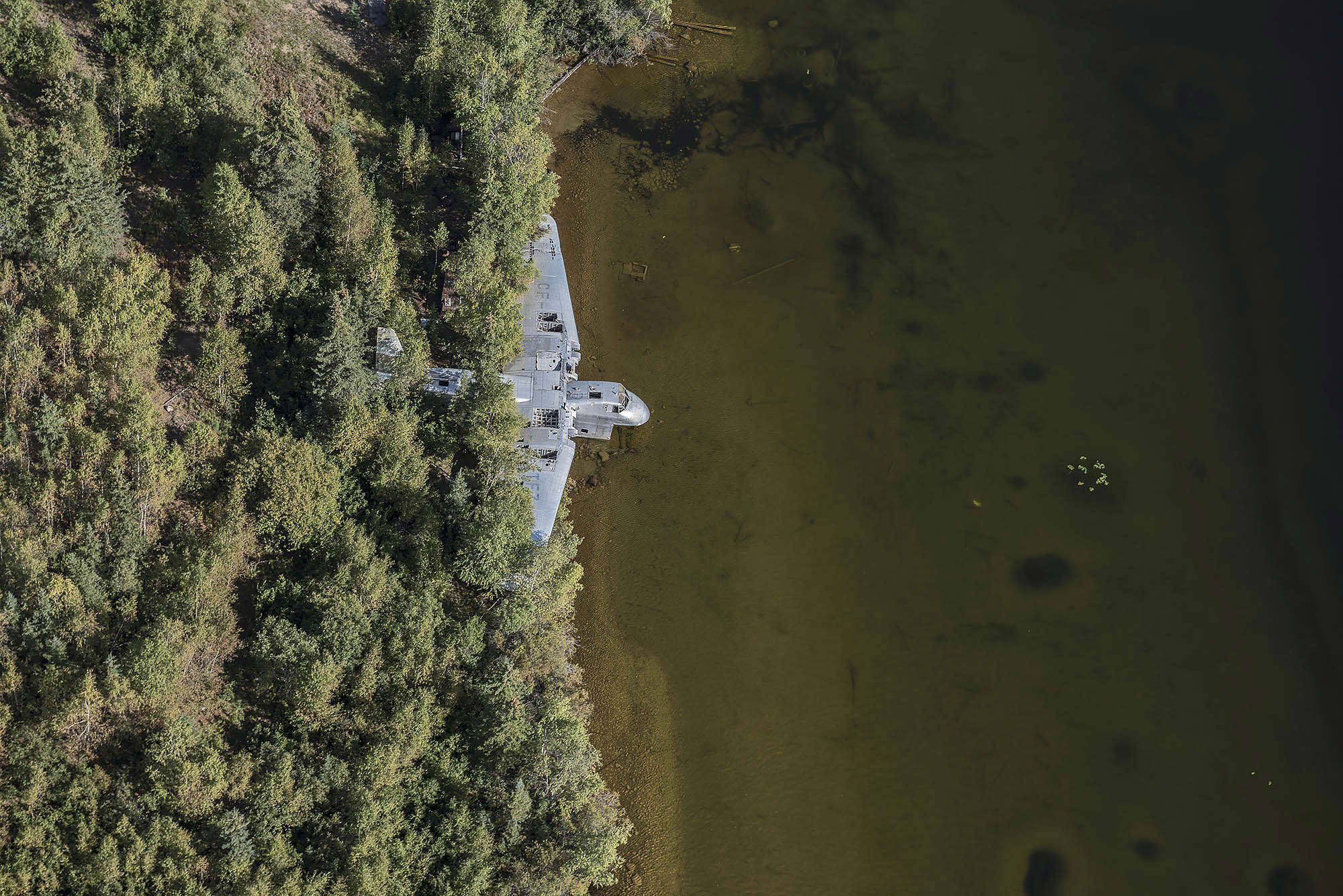 Slide 13 of 28: The abandoned plane rots away quietly as it rests on the side a lake in Canada.