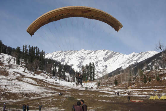 Slide 3 of 99: Tourists paraglide after fresh snowfall in Solang Nallah