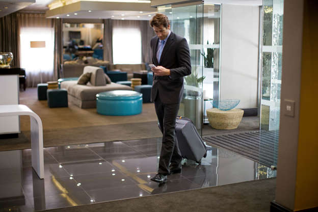 A man walks in to a hotel lobby with luggage.