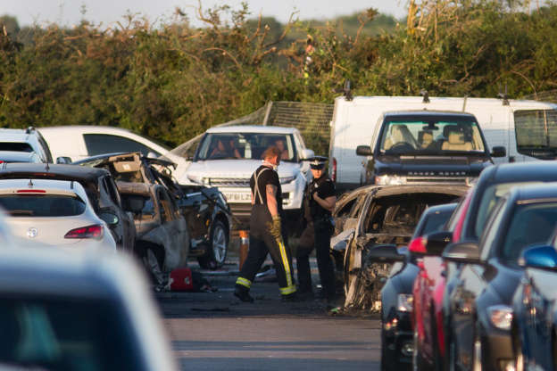 Emergency services inspect the crash site at Blackbushe Airport in Hampshire, after four people died when a private Phenom 300 jet crash-landed in a car auction site and burst into flames as it approached the runway in Farnborough, Britain, 31 July 2015. EPA