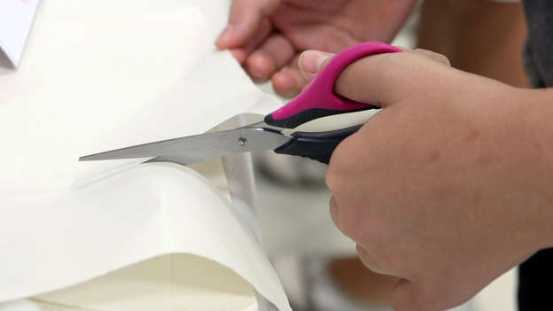 A person cuts paper with scissors for left-handed.